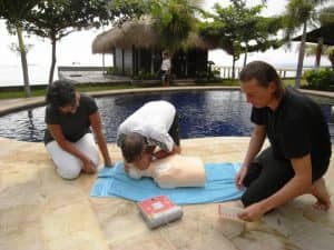 cpr1st Drei Taucher üben Wiederbelebung an einer Puppe